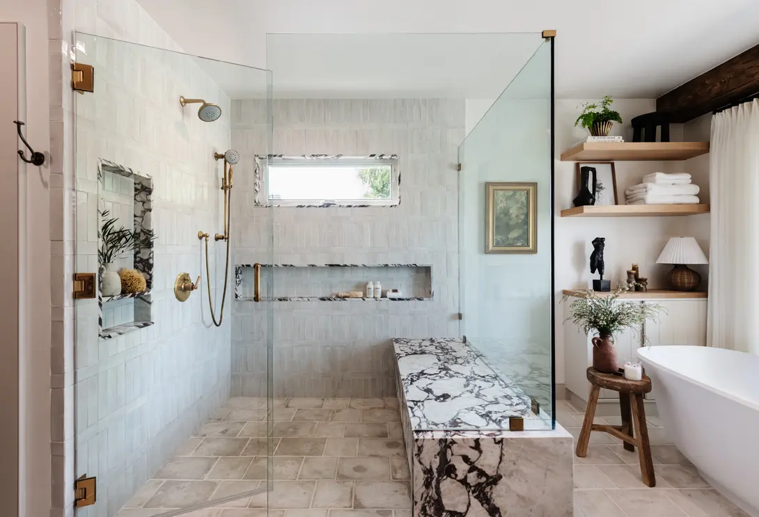Modern bathroom featuring a glass-enclosed shower, marble bench, and neutral decor.