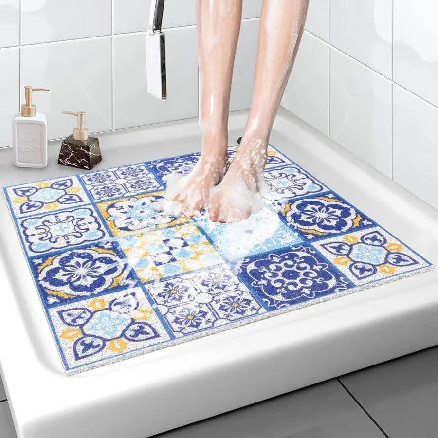 Person's feet on a colorful bath mat in a shower, with soap bubbles.