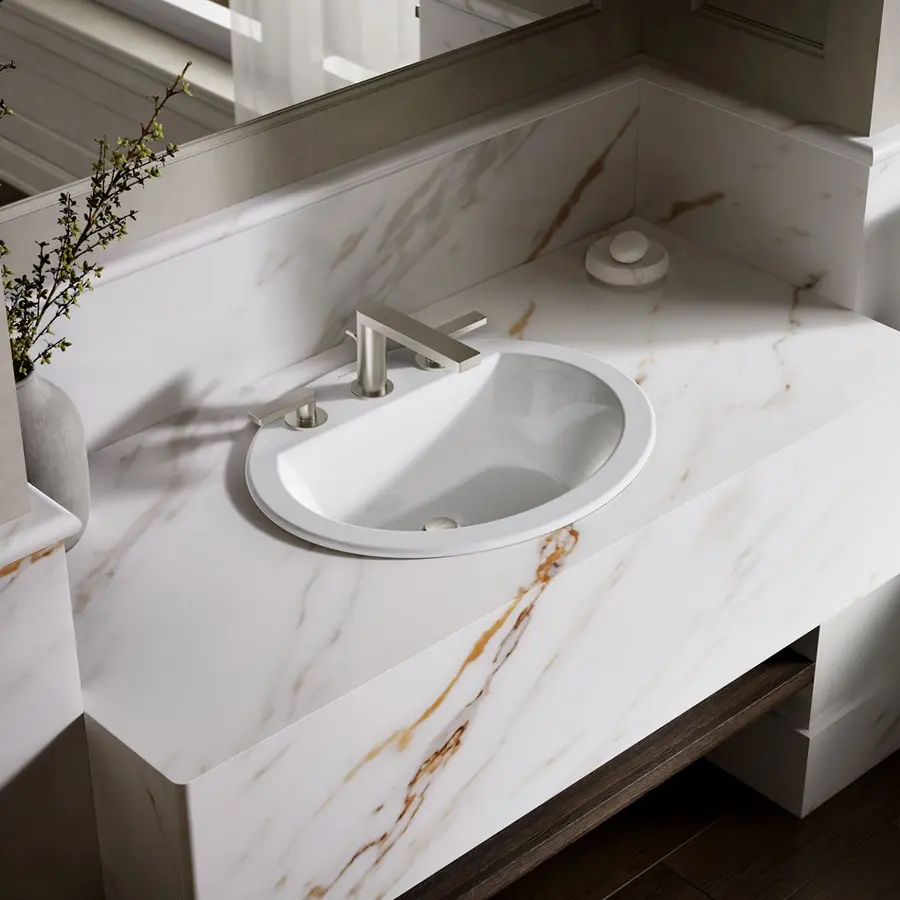 A circular white sink on a marble countertop with a modern faucet and visible drain.