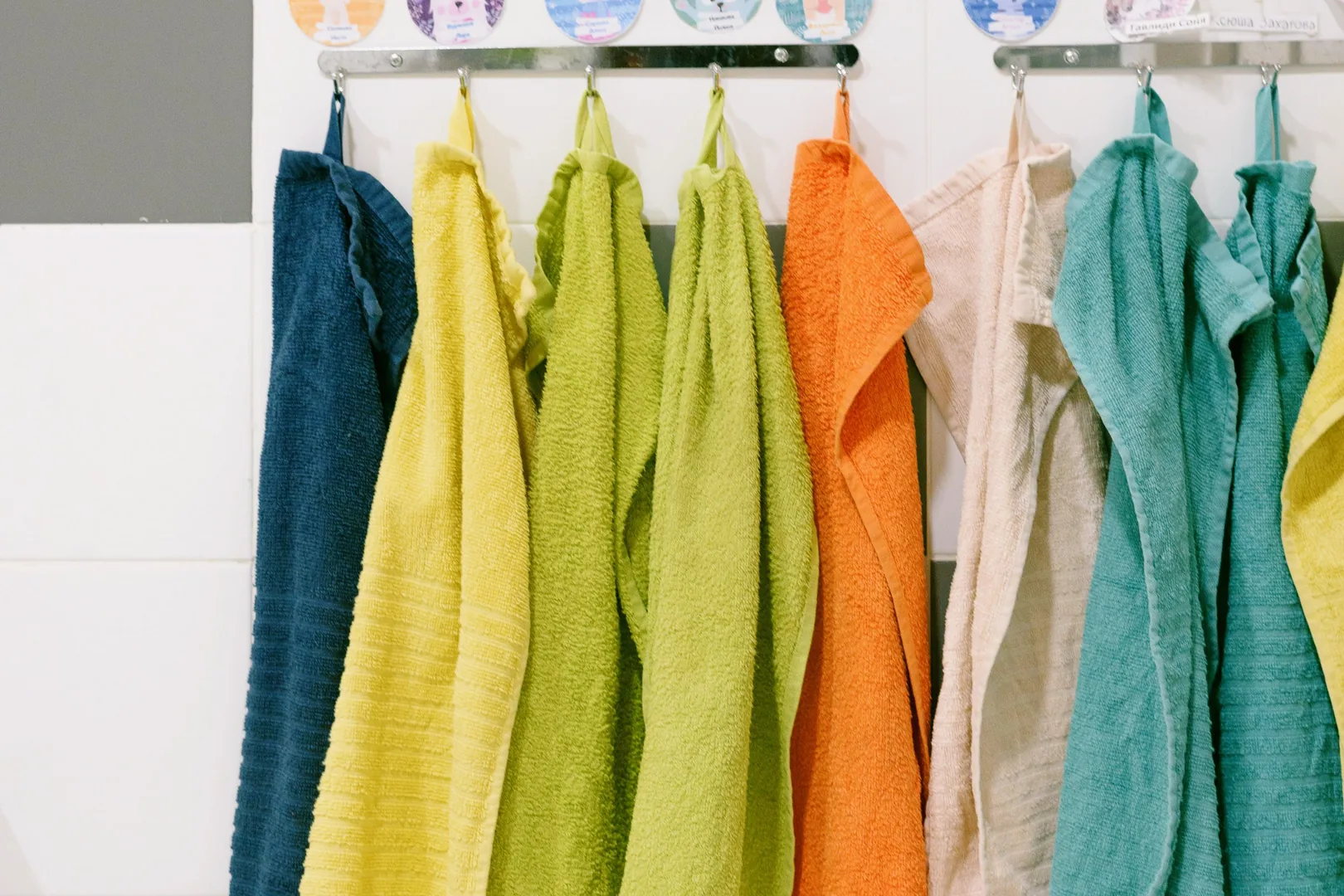 Colorful bath towels spread across a wall-mounted towel rail.