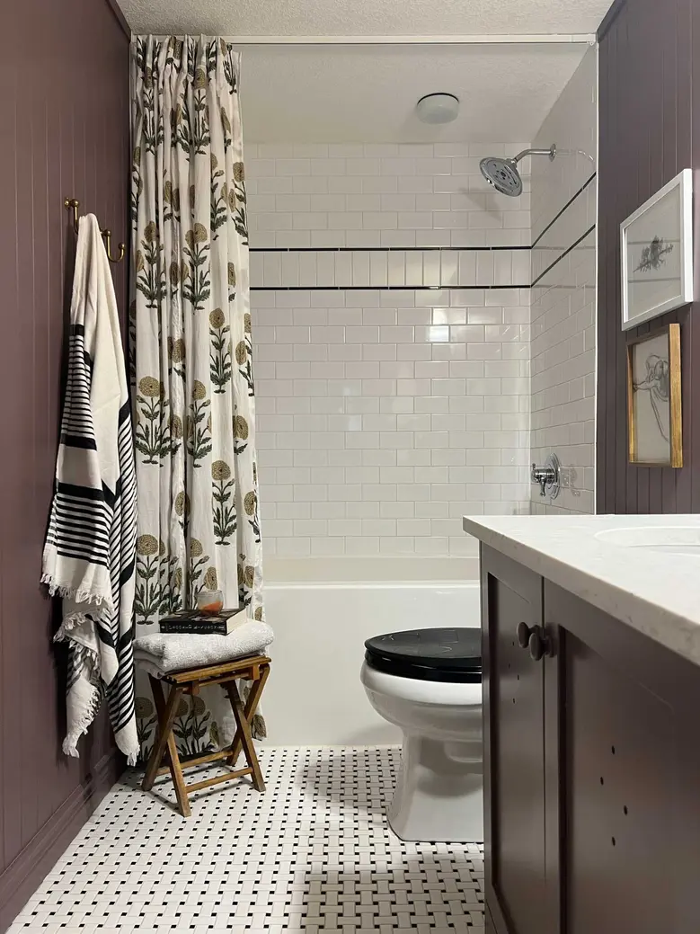 Modern bathroom featuring a shower curtain, patterned curtain rod, and dark cabinetry.