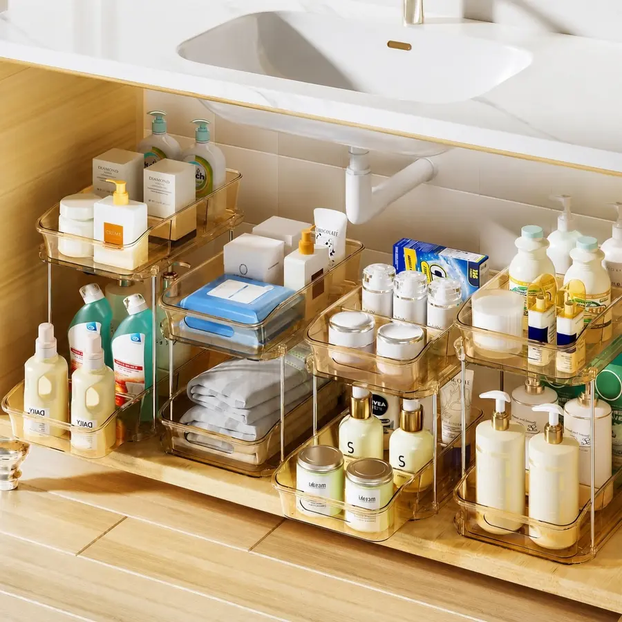 Organized bathroom sink cabinet with clear bins holding various toiletries and cleaning supplies.