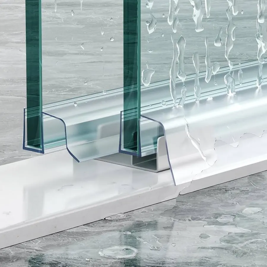 Frameless glass shower door with a clear bottom seal above a shower tray, water droplets visible.