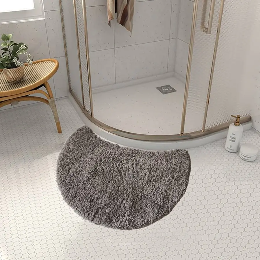 A gray bath mat curled at the edges in a tiled bathroom setting.