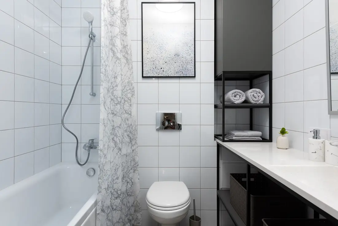 A clean, patterned fabric shower curtain hanging in a bright, modern bathroom with a bath and storage.