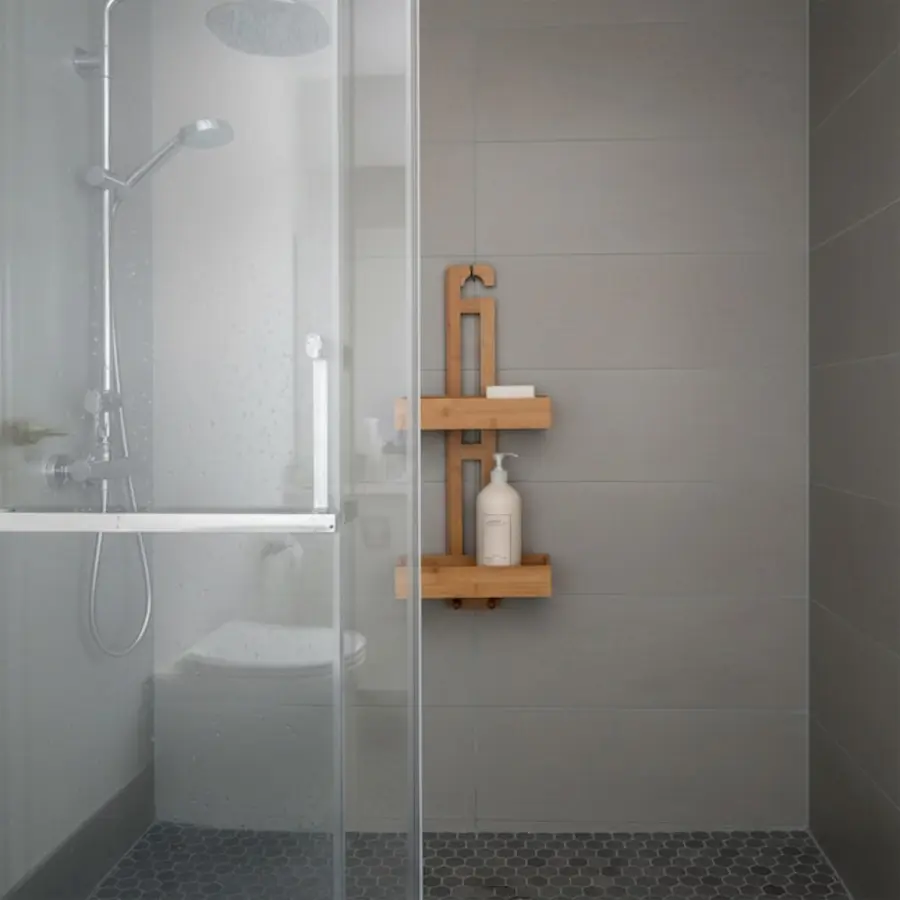 A wooden shower caddy mounted on a tiled wall in a glass-enclosed shower.
