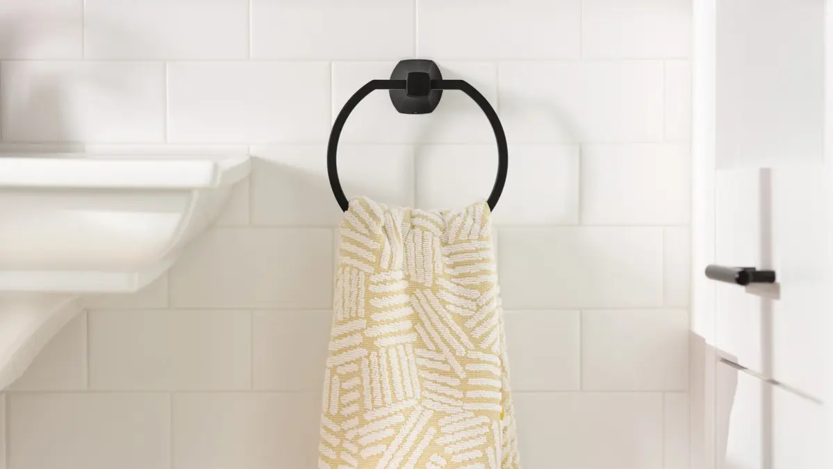 Towel ring mounted on a wall beside a bathroom sink, holding a textured towel.